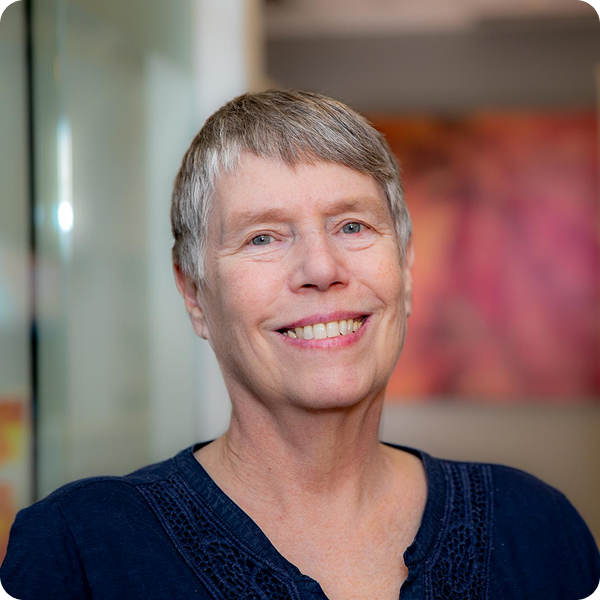 Woman smiling with a pink painting in the background.