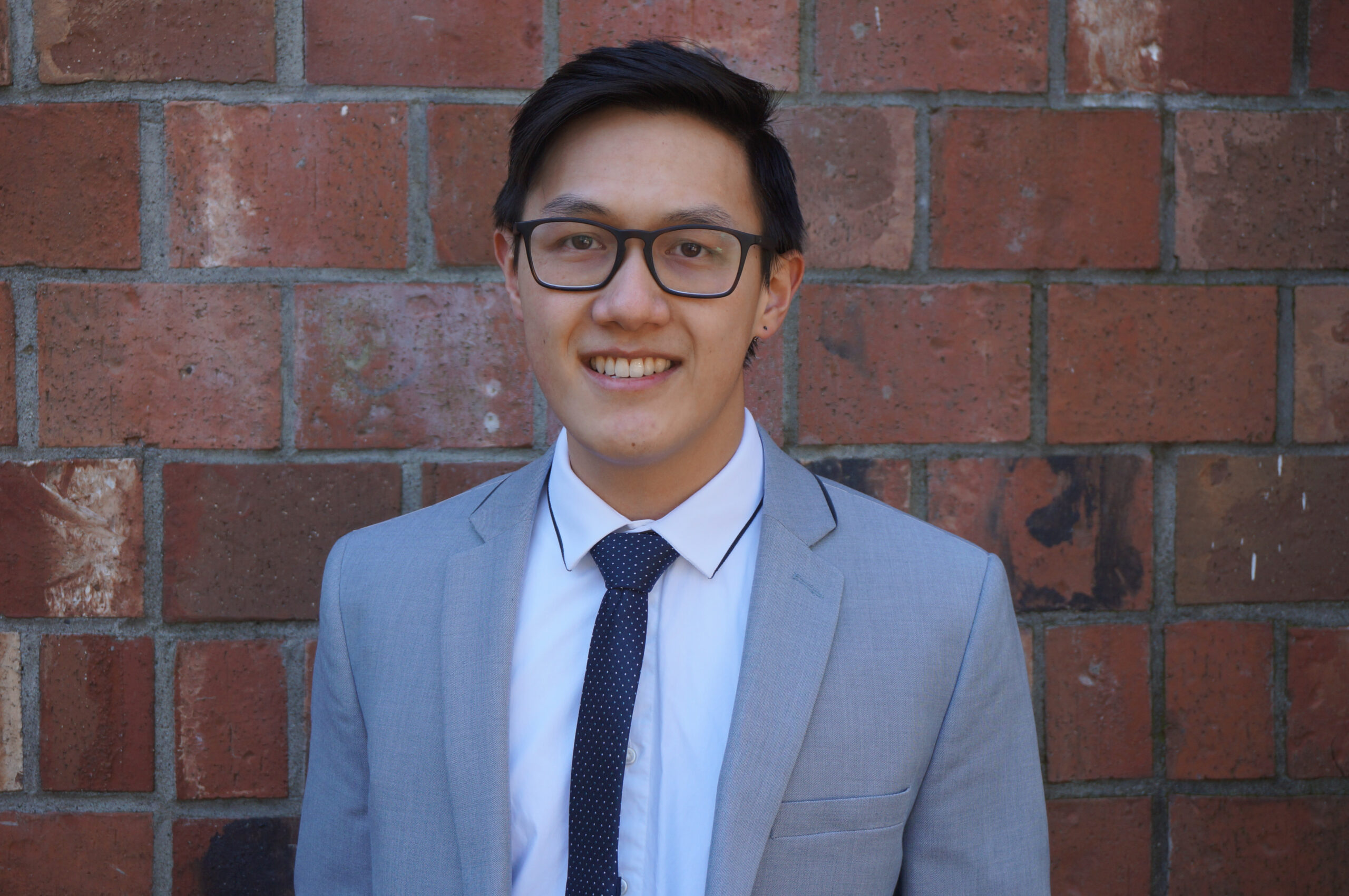 Dr. Stephen Wong standing in front of a red brick wall smiling.
