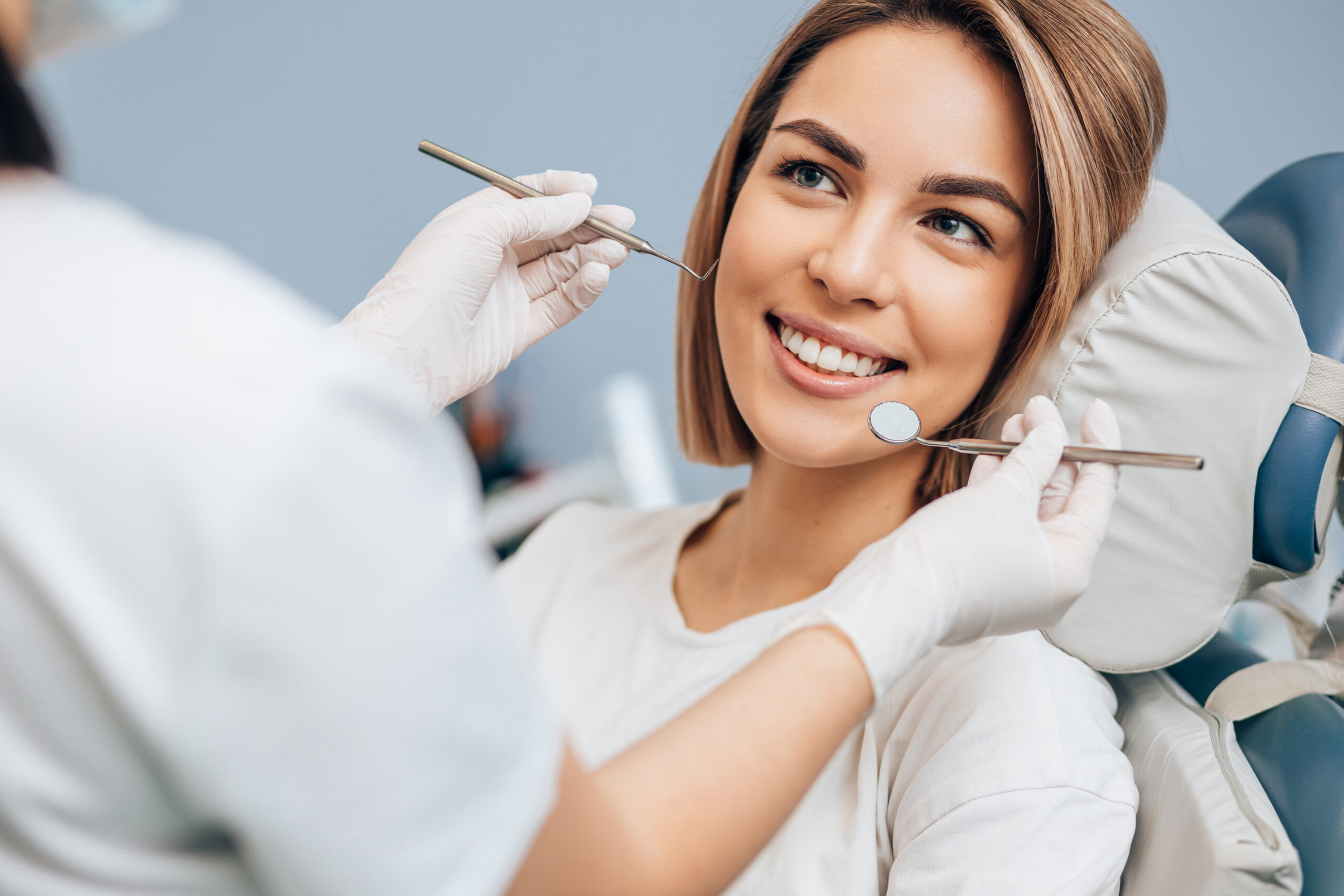 Woman siting in a dentists chair smiling getting a dental check up.