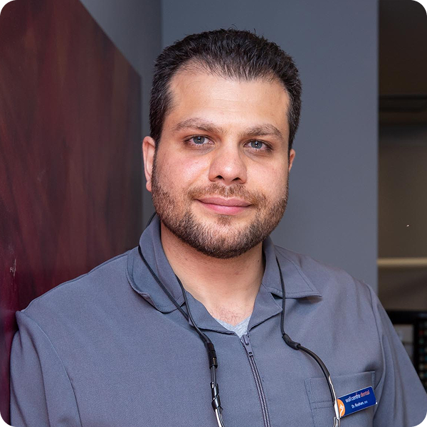 Dr. Parviz Roshanzamir leaning against a wall smiling with the office in the background.